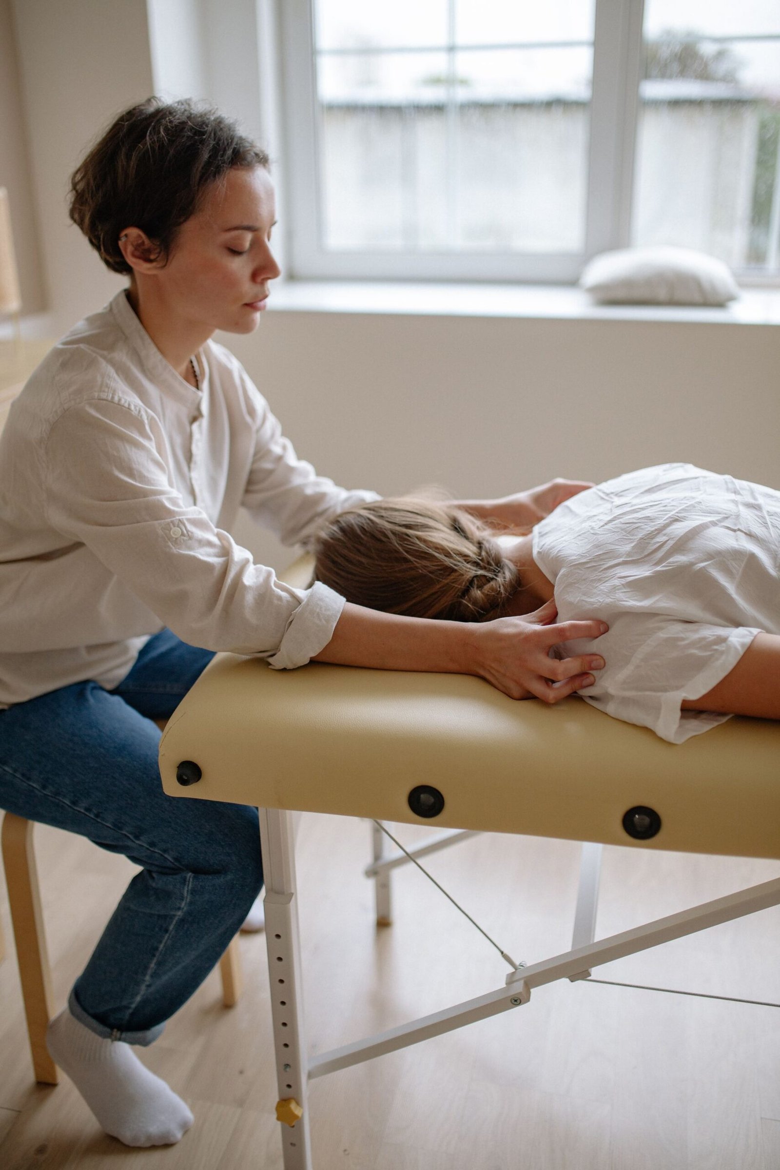 A therapist treating a woman on a treatment table