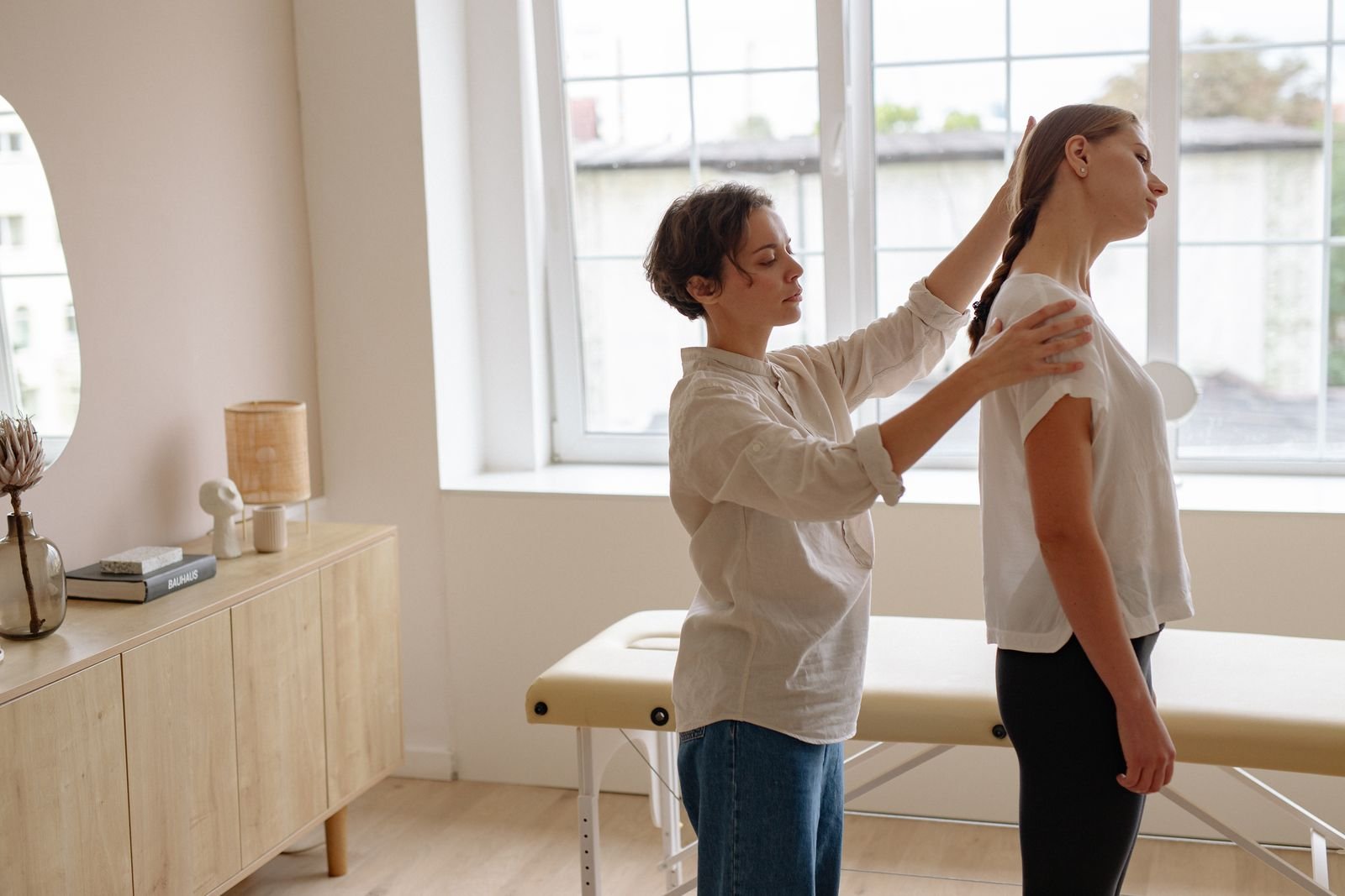 A chiropractor adjusting a patient's posture in a bright clinic